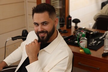 Young man with fresh haircut and groomed beard in barbershop