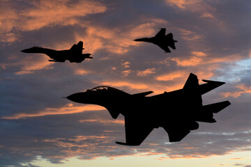 Silhouettes of jet fighters in cloudy sky