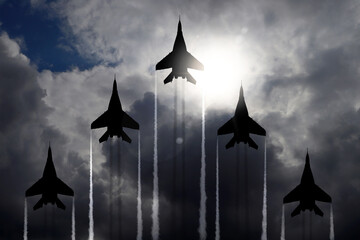 Silhouettes of jet fighters in cloudy sky