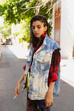 Portrait Of Young Woman Smoking While Standing On Footpath