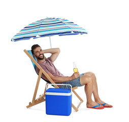 Happy man with bottle of beer resting in deck chair near cool box on white background