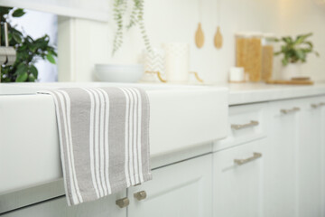Fototapeta na wymiar Clean towel hanging on white sink in kitchen