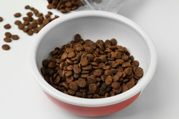 Feeding bowl with dry cat food on white background, closeup