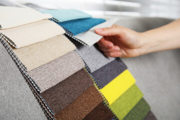 Woman choosing fabric among colorful samples on sofa, closeup