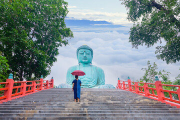 Tourists walk up the stairs to see the Big Buddha (Daibutsu) at Wat Phra That Doi Phra Chan,...