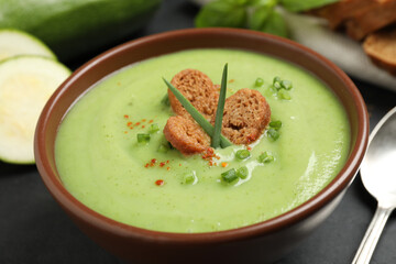 Tasty homemade zucchini cream soup in bowl on table, closeup