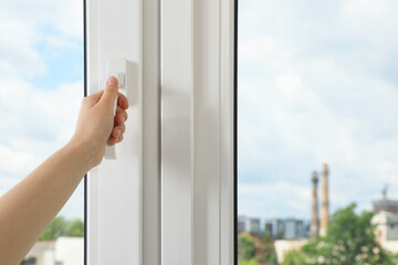 Woman opening white plastic window indoors, closeup. Space for text