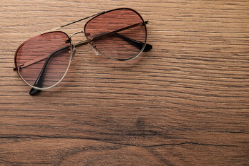 Fototapeta na wymiar New stylish sunglasses on wooden table, top view. Space for text
