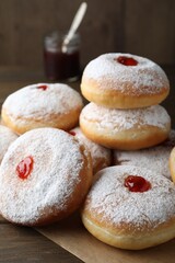 Many delicious donuts with jelly and powdered sugar on wooden table, closeup