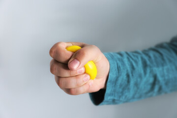 Man squeezing antistress ball on grey background, closeup