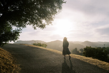 Woman walking on empty road at sunset