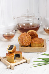 Moon cake Mooncake table setting - Round shaped Chinese traditional pastry with tea cups on wooden background, Mid-Autumn Festival concept, close up.