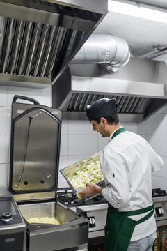 chef cooking vegetables in the industrial fryer in a kitchen