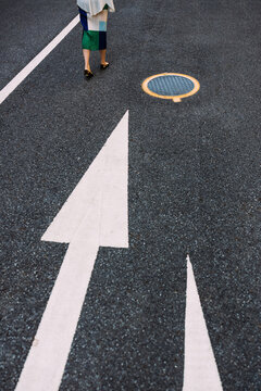  Manhole and road sign and woman's leg