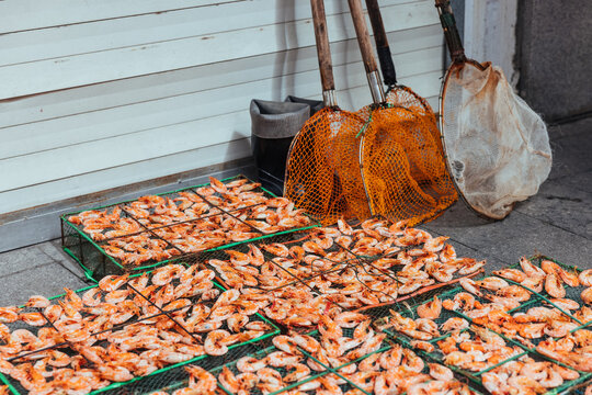 Drying Shrimps Under Sunlight With Fishing Tools By Side.