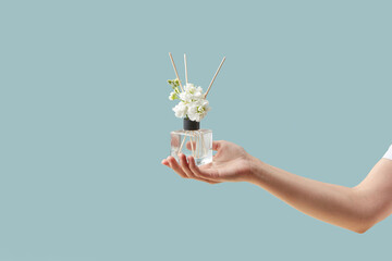 Woman holding aroma diffuser with jasmine flowers.