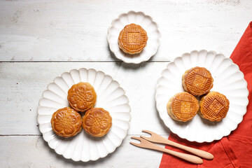 Moon cake Mooncake table setting - Round shaped Chinese traditional pastry with tea cups on wooden background, Mid-Autumn Festival concept, close up.