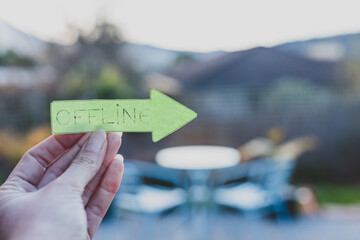 unplugging and enjoying life outdoor, hand holding Offline arrow sign in front of backyard bokeh