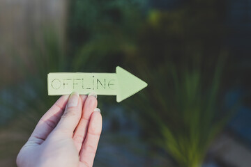 unplugging and enjoying life outdoor, hand holding Offline arrow sign in front of backyard bokeh