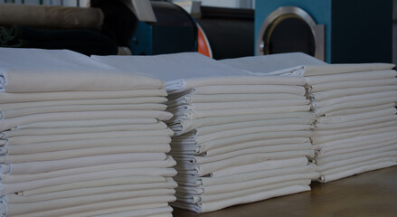 Folded white sheets in an industrial laundry.