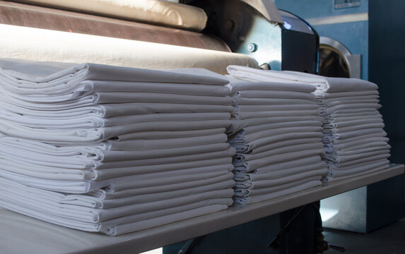 Folded white sheets in an industrial laundry.
