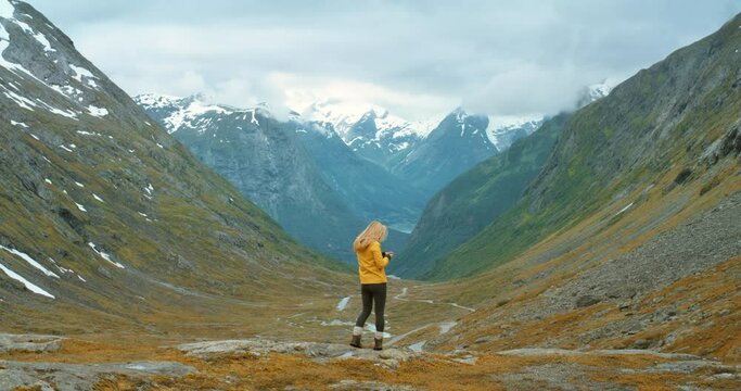 Hiker taking mountain pictures on a phone for social media while hiking, traveling and exploring remote Norway landscape. Woman, tourist or traveler enjoying peaceful nature and hills covered in snow