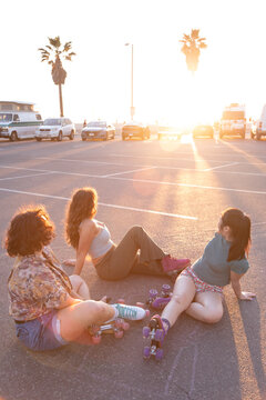 Stylish Gen Z people laughing on the floor wearing rollerskates
