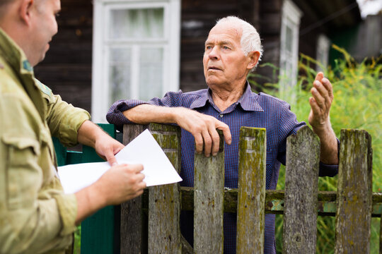 Grandfather Talking To Census Agent Standing At Fence Of His Country House