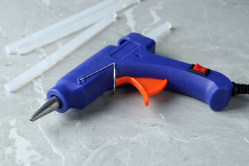 Hot glue gun and sticks on light grey marble table