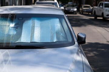 Closeup of protective reflective surface under the windshield of the passenger car parked on a hot...