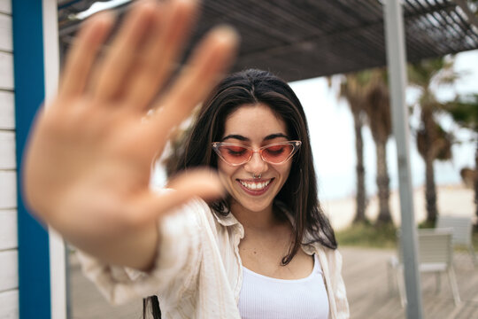 Portrait of happy stylish woman covering the camera with her hand