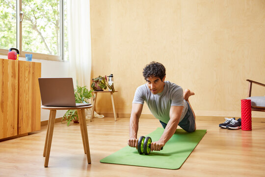 Sportsman watching video and exercising with ab wheel