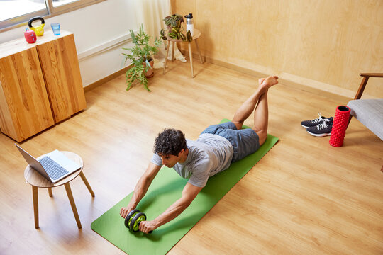 Athlete exercising with ab wheel during online workout
