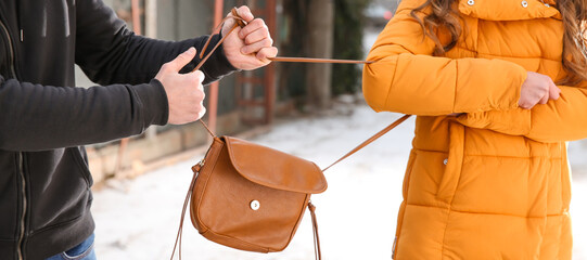 Male thief stealing bag from young woman outdoors