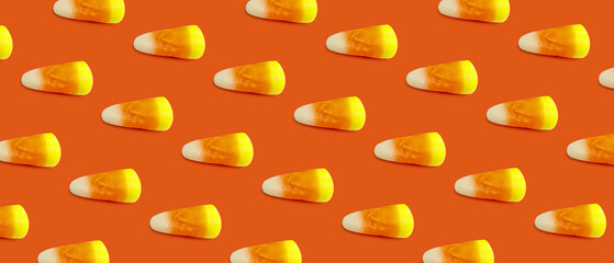 Tasty corn candies for Halloween on orange background