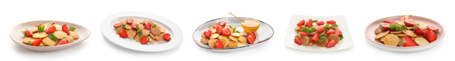 Set of plates with mini pancakes and strawberry on white background