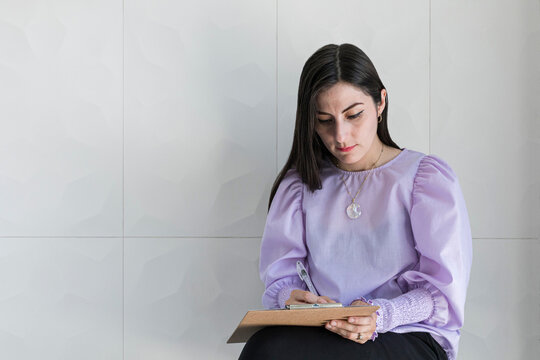 Woman writing on a piece of paper on a wooden board