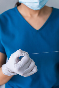 A dentist with mask and gloves holding dental floss 