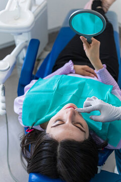 Woman lying in a blue dentist's chair looking at her teeth