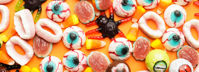 Heap of tasty jelly candies for Halloween party on orange background