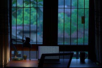 silhouette of a desk and laptop in a window early morning