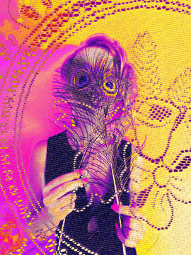 girl holding two peacock featers over her eyes