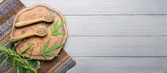 Spoons with hemp seeds and leaves on wooden background with space for text
