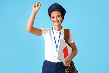 Young postwoman with envelopes on blue background