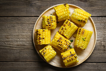 corn food , sweet corn cooked on wooden plate background, ripe corn cobs grilled sweetcorn for food vegan dinner or snack - top view