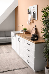 Interior of stylish kitchen with white counters, sink and pegboard