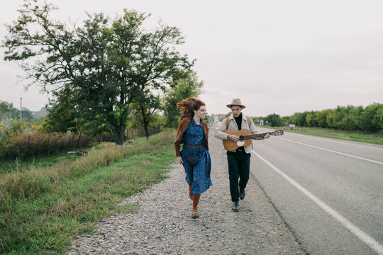 young couple having fun walking along the freeway with guitar