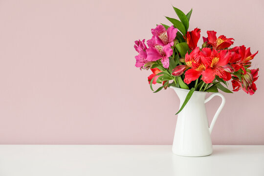 Vase with bouquet of beautiful alstroemeria flowers near color wall