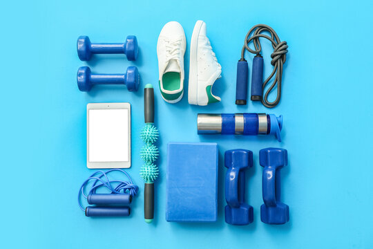 Different sports equipment, shoes and tablet computer on color background
