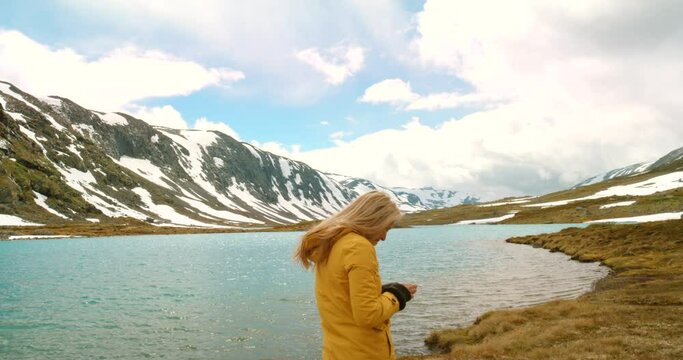 Hiker taking picture on phone of mountains and lake for social media and hiking, traveling or exploring. Global warming activist, tourist or traveler enjoying nature in remote winter Norway landscape